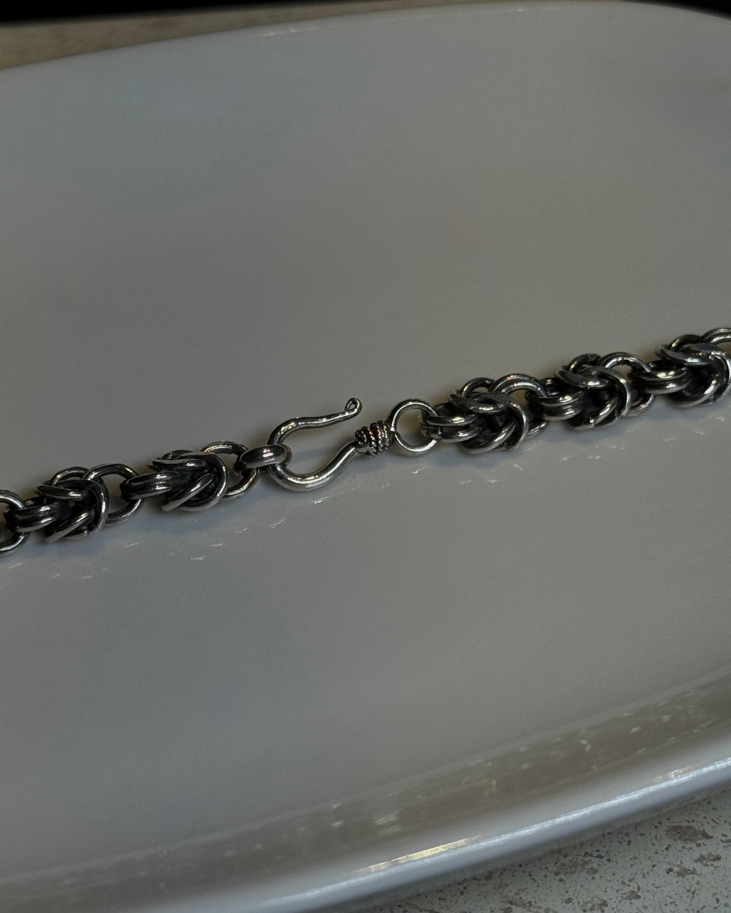 Silver chain necklace on a white plate with a dark background
