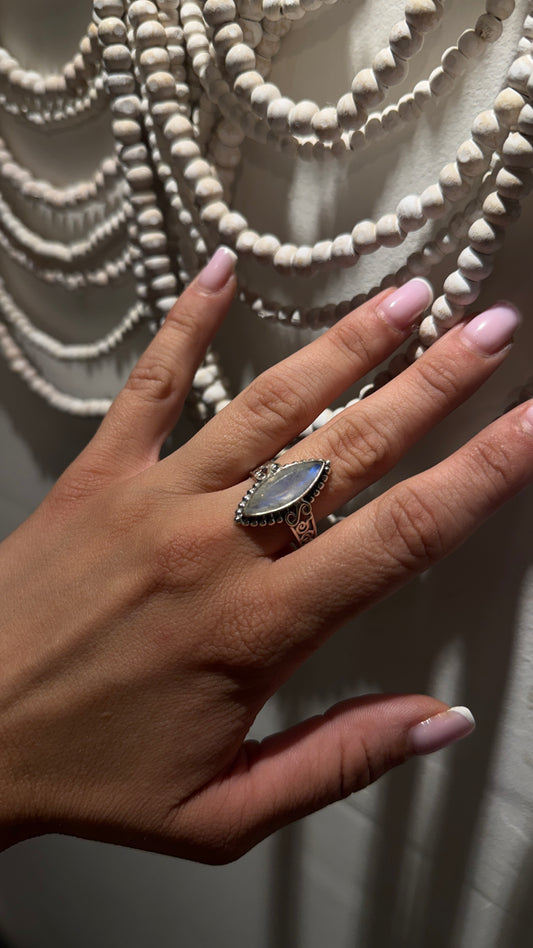 Rainbow moonstone marquise ring in sterling silver with filigree band on hand.
