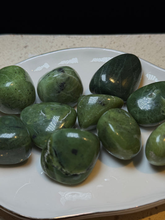 Polished green jade tumbled stones on a white dish