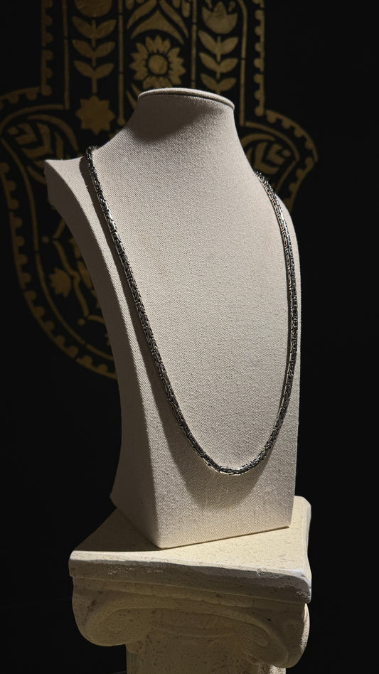 Handmade 30-inch Balinese Byzantine chain displayed on a cream velvet jewelry bust, with black and gold mystical backdrop