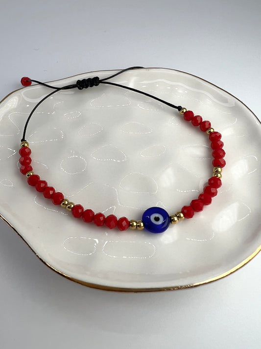 Evil eye bracelet with red beads on a plate