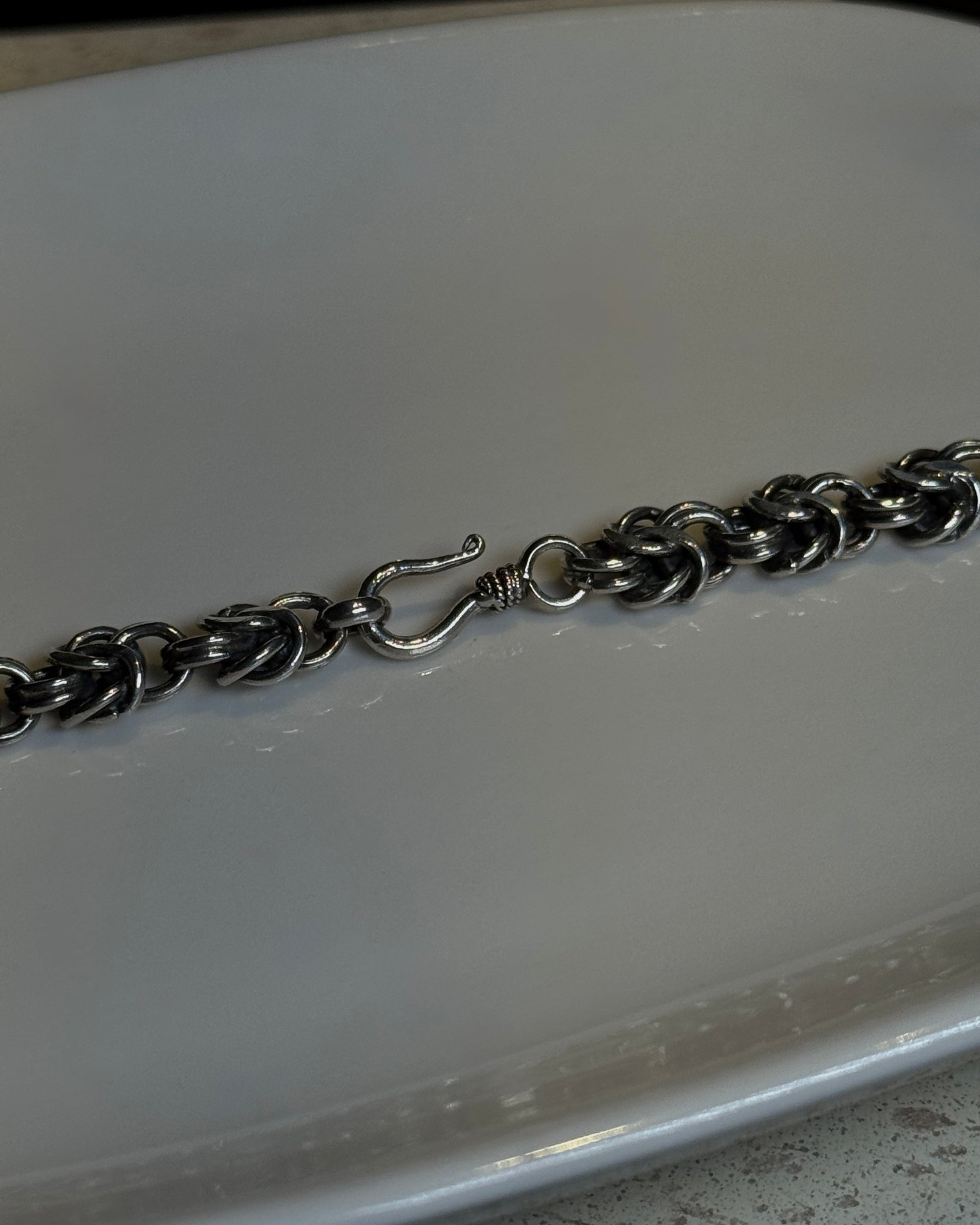 Silver chain necklace on a white plate with a dark background
