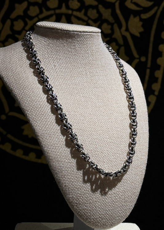 Necklace on a mannequin bust against a dark patterned background
